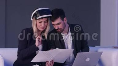 女建筑师戴着虚拟现实耳机，用笔记本电脑向男同事展示设计图